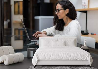 Smiling attractive young woman using laptop communicating working online at home Wall mural